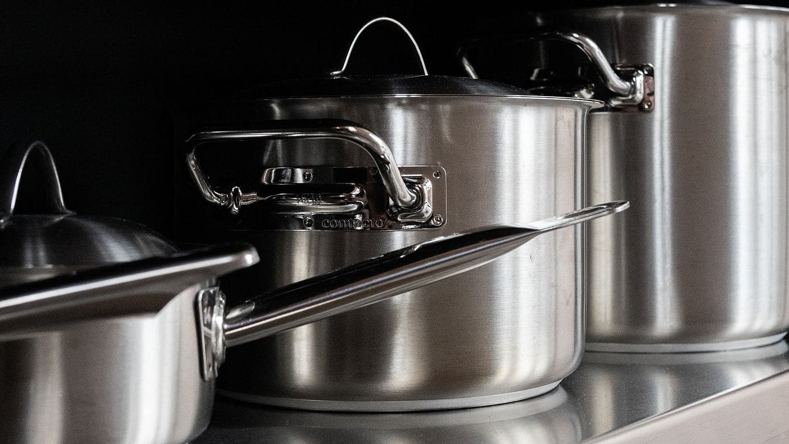 A stack of stainless steel pots and pans with lids.