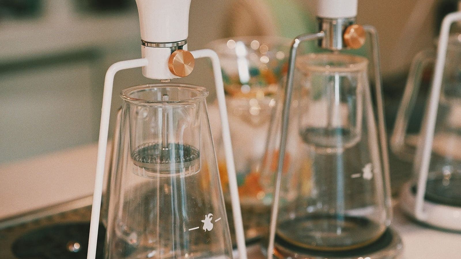 A row of glass pour-over coffee brewers on a cafe counter.