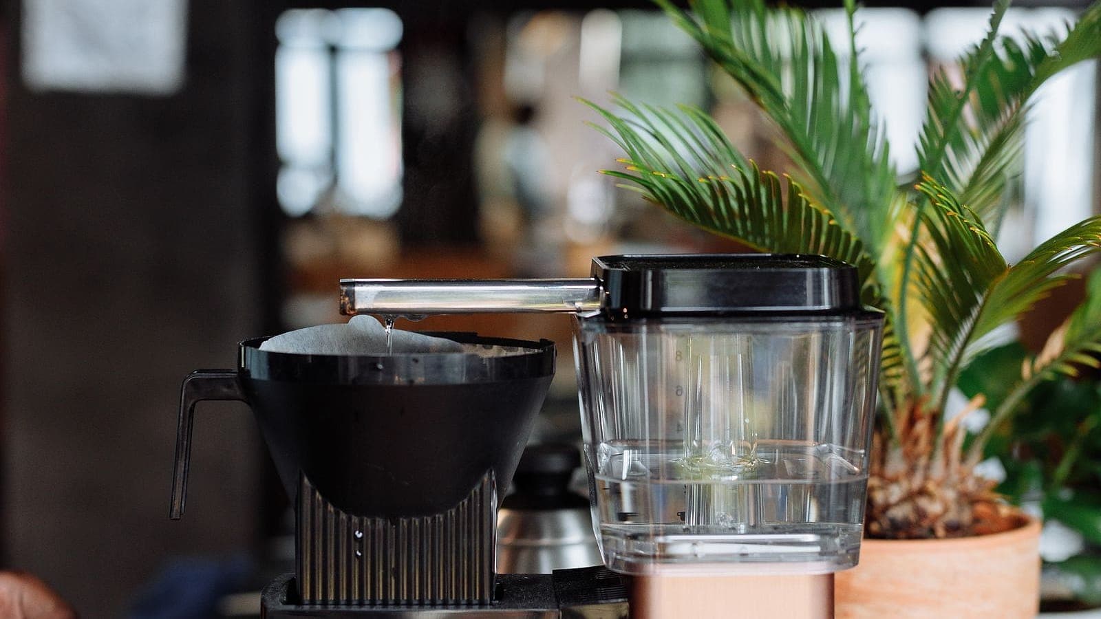 A copper drip coffee machine brewing into a glass carafe.