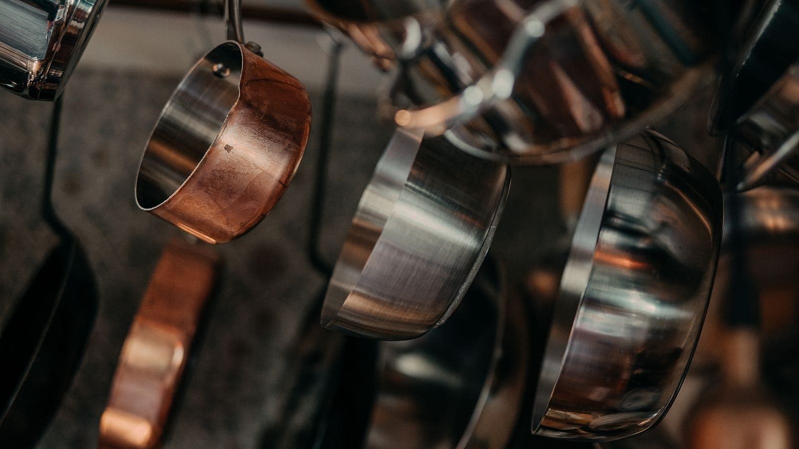 Copper and stainless-steel pans hanging from a kitchen rack