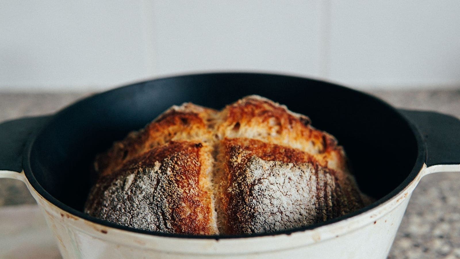 A golden, crusty sourdough loaf baked in an enameled cast-iron Dutch oven