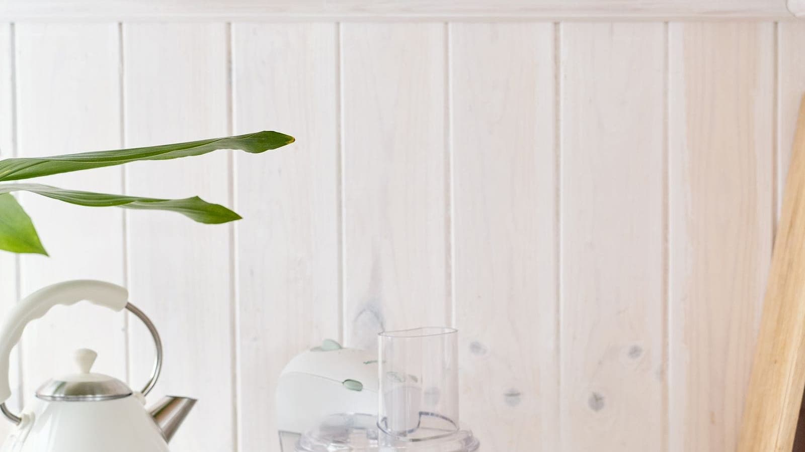 A food processor and kettle on a bright kitchen counter