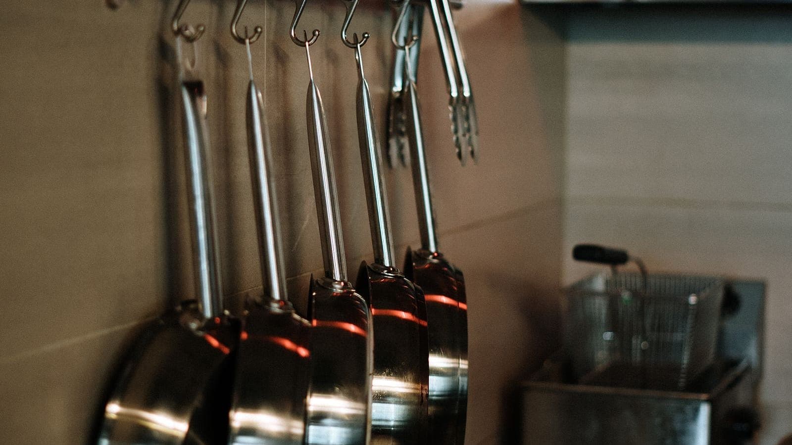 A row of frying pans hanging from a kitchen rail
