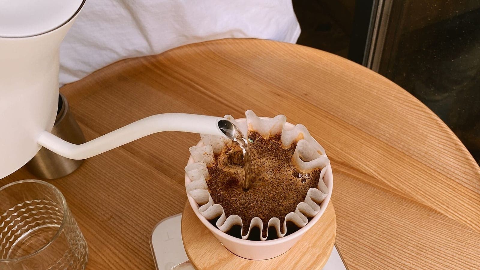 Hot water poured from a gooseneck kettle into a paper filter, blooming the coffee grounds.