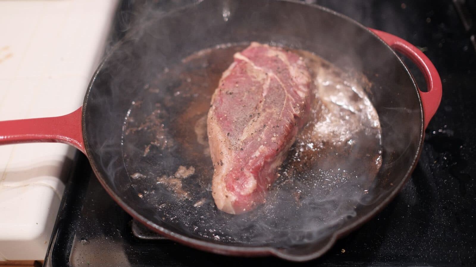 A steak searing in a hot cast-iron skillet