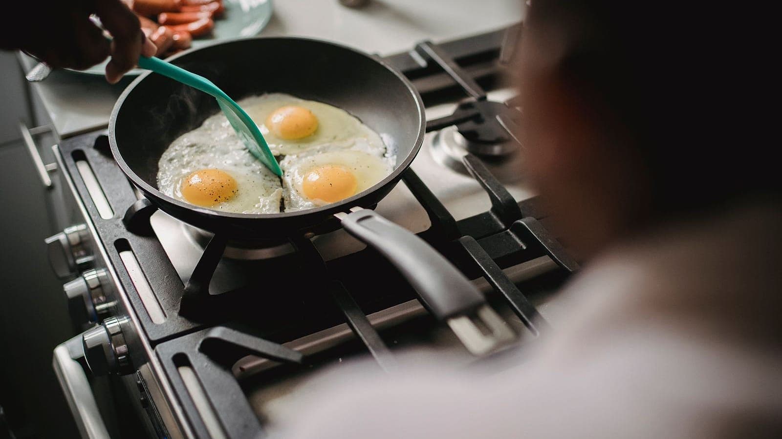 Two eggs frying in a black nonstick pan on a stovetop
