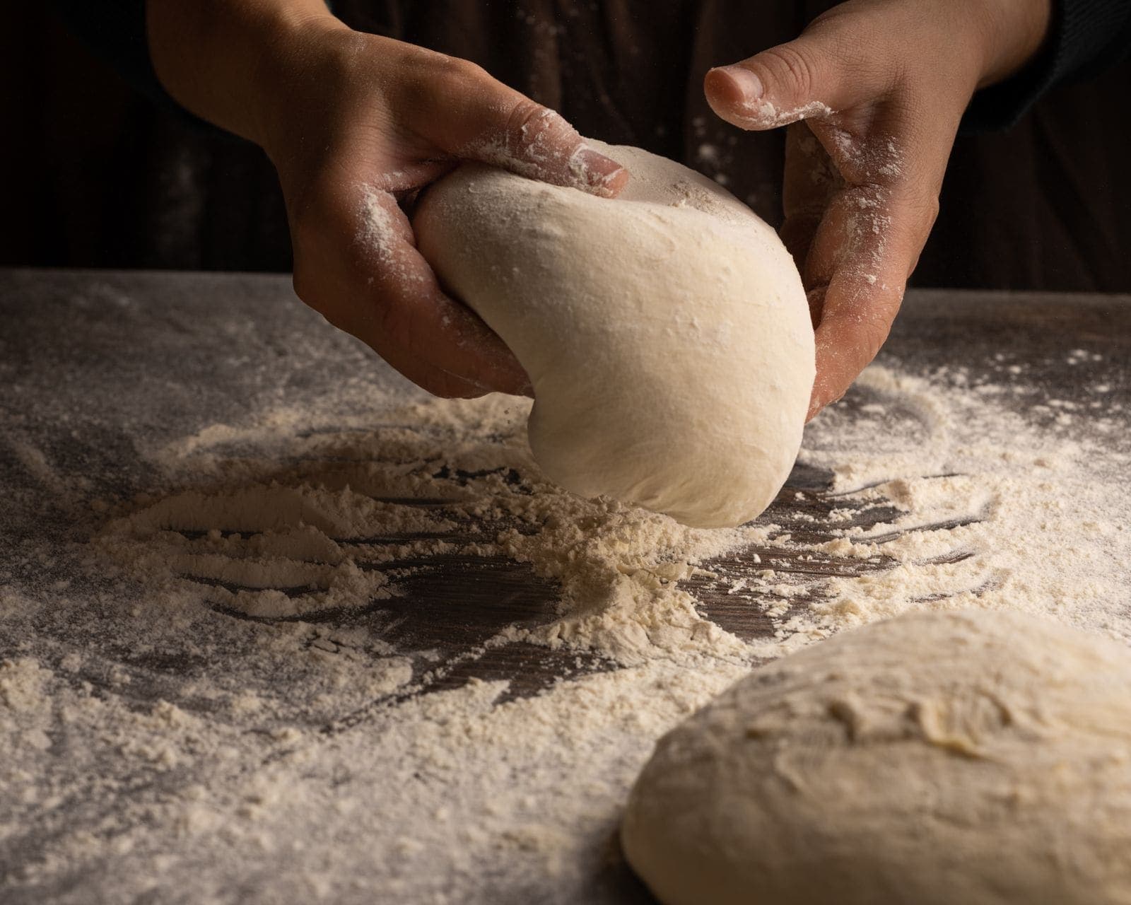 Shaping a round of bread dough on a floured wooden surface