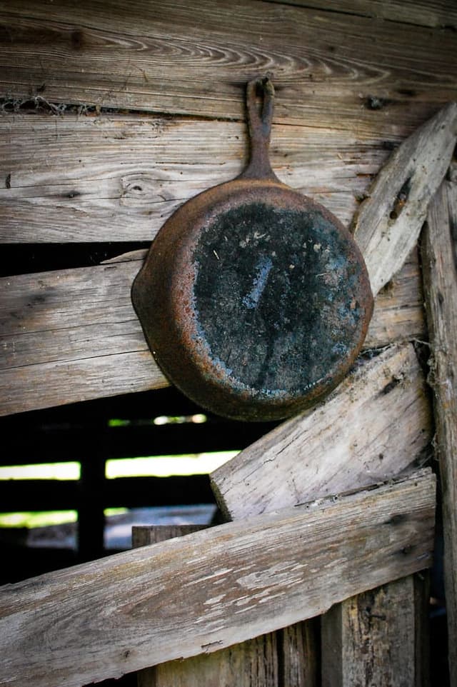 An old weathered cast-iron pan resting on rough barn wood