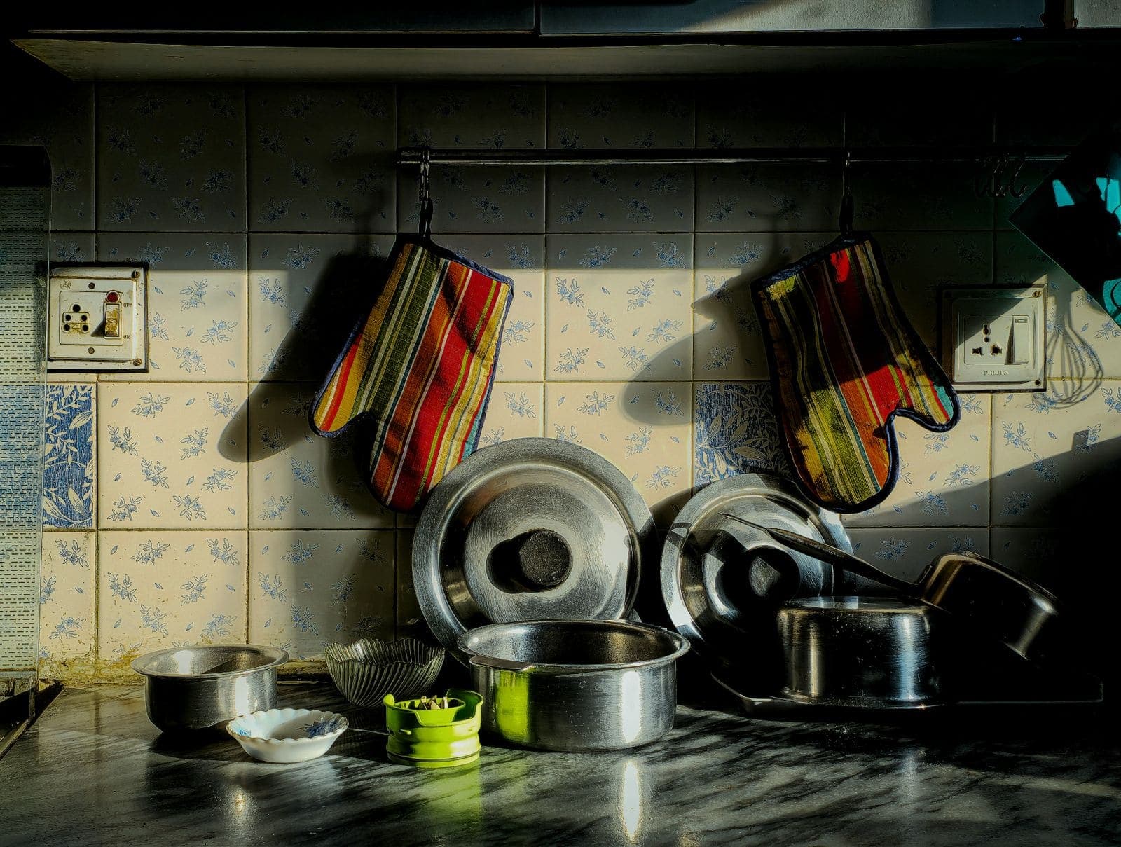 A well-used home kitchen with pots and oven mitts hanging above the stove